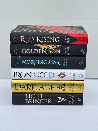 Stack of books titled 'Red Rising', 'Golden Son', 'Morning Star', 'Iron Gold', 'Dark Age', and 'Light Bringer' by Pierce Brown on a light gray background.